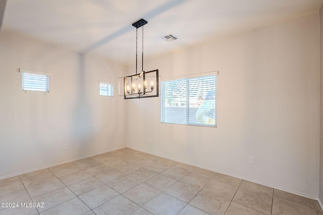 spare room featuring a notable chandelier and light tile patterned floors