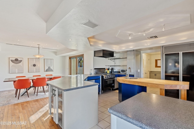 kitchen with high end appliances, a center island, sink, and decorative light fixtures