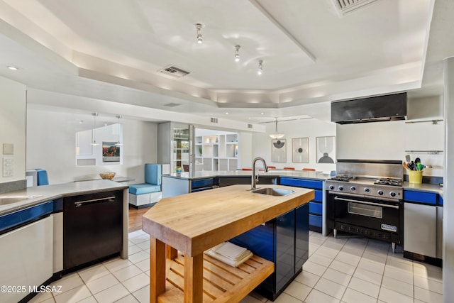 kitchen featuring sink, blue cabinetry, dishwasher, premium stove, and decorative light fixtures