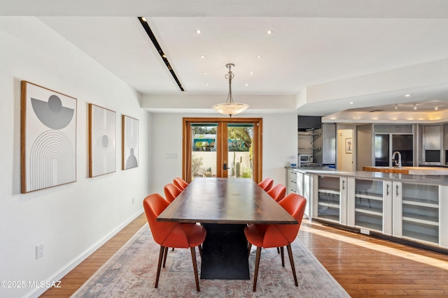 dining area featuring french doors, sink, and light wood-type flooring