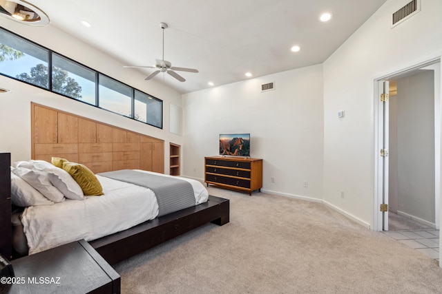 bedroom with ceiling fan, light colored carpet, and a towering ceiling