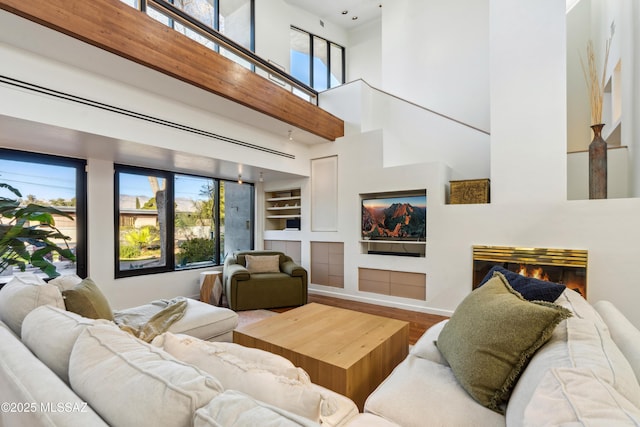 living room with wood-type flooring, built in features, and a high ceiling