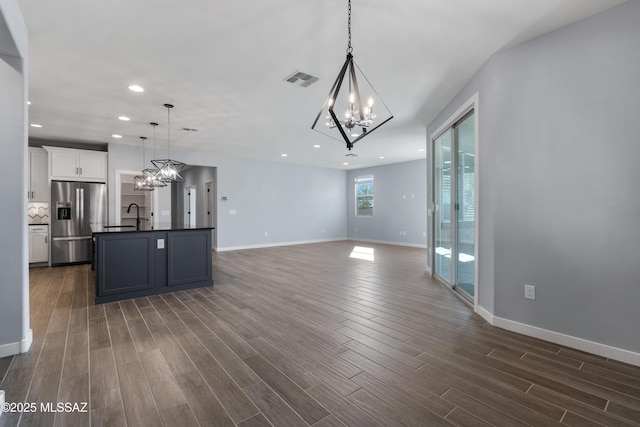 unfurnished living room featuring dark hardwood / wood-style floors, sink, and a chandelier