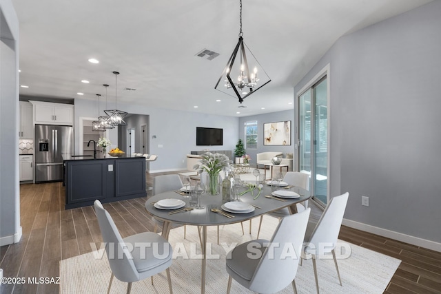 dining area featuring sink, dark wood-type flooring, and a chandelier