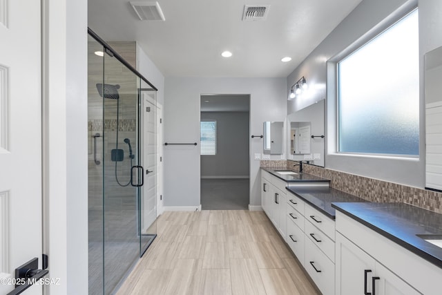 bathroom with vanity, backsplash, and a shower with shower door