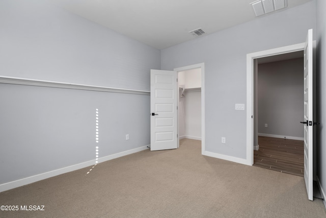 unfurnished bedroom with light colored carpet, a closet, and a walk in closet