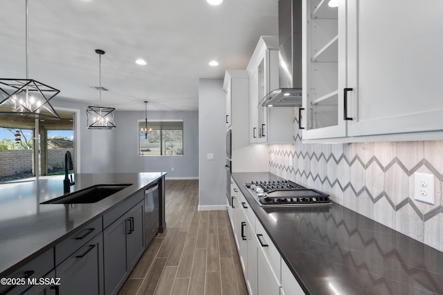 kitchen featuring sink, hanging light fixtures, stainless steel appliances, white cabinets, and wall chimney exhaust hood