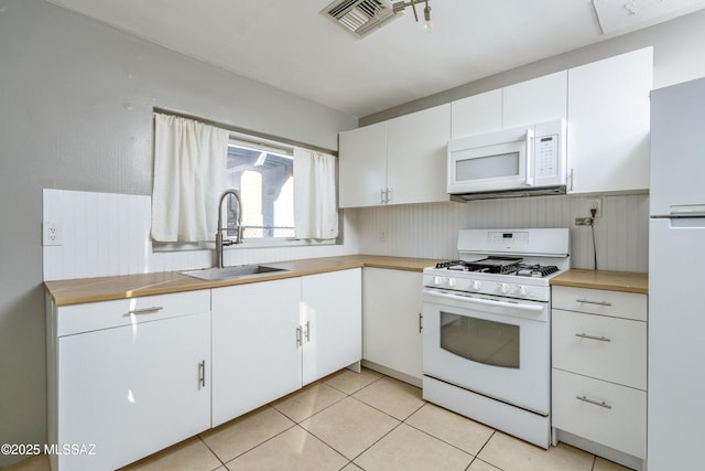 kitchen with light tile patterned floors, sink, white appliances, and white cabinets