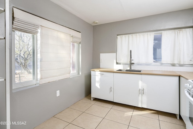 kitchen featuring light tile patterned floors, sink, white cabinetry, and white range