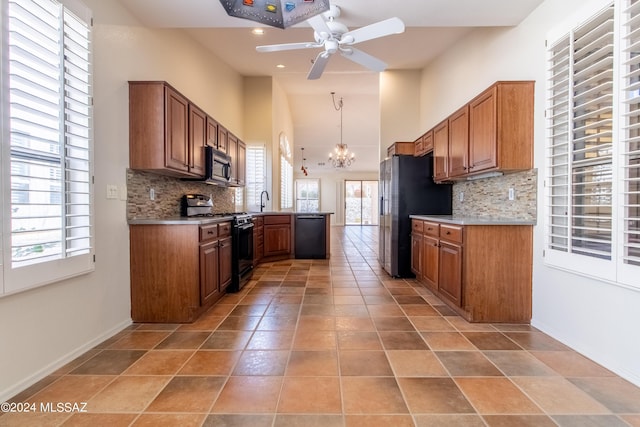 kitchen with decorative backsplash, a wealth of natural light, hanging light fixtures, and black appliances