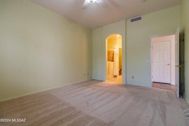 unfurnished bedroom featuring ceiling fan, ensuite bathroom, and light carpet