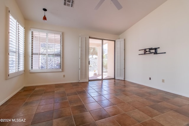 spare room featuring ceiling fan, dark tile patterned floors, and vaulted ceiling