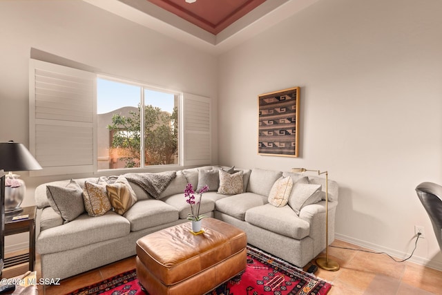 living room with light tile patterned floors and a tray ceiling