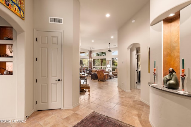 hall with a towering ceiling and light tile patterned flooring