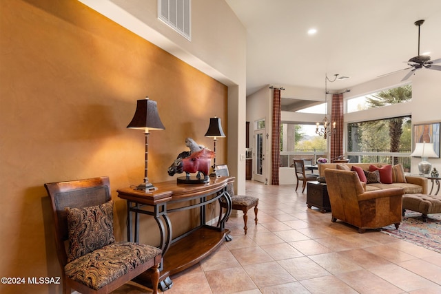 interior space with light tile patterned floors, a towering ceiling, and ceiling fan with notable chandelier