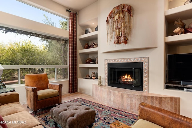 living room featuring built in shelves and a tile fireplace