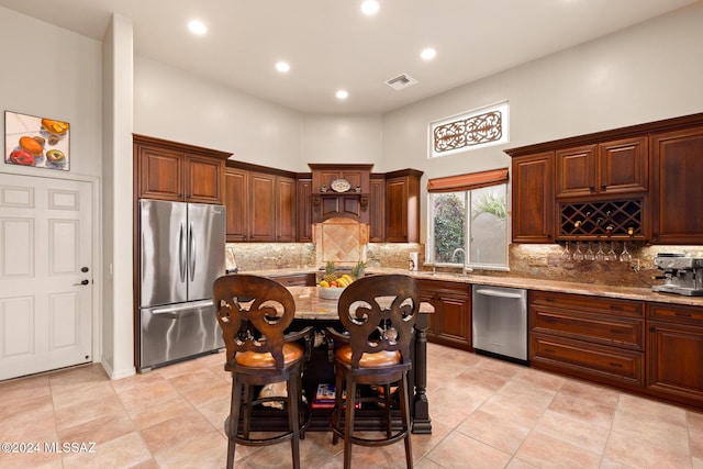 kitchen featuring a breakfast bar, a high ceiling, sink, light stone countertops, and appliances with stainless steel finishes