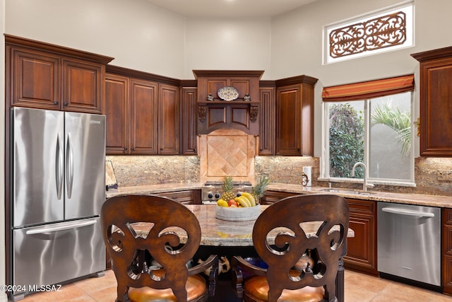 kitchen with light stone counters, sink, light tile patterned floors, and stainless steel appliances