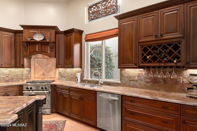 kitchen with decorative backsplash, sink, light stone counters, and appliances with stainless steel finishes