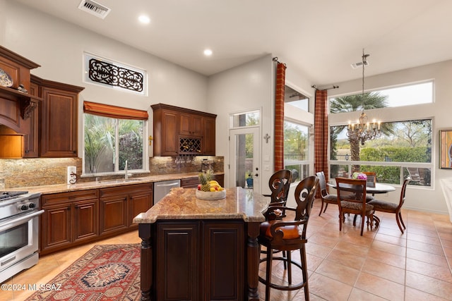 kitchen featuring appliances with stainless steel finishes, backsplash, sink, an inviting chandelier, and a kitchen island