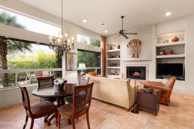 tiled dining room with a tile fireplace, ceiling fan with notable chandelier, and built in features