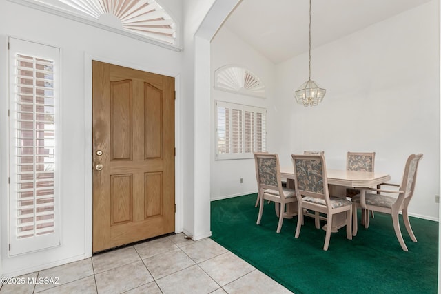 tiled dining area featuring an inviting chandelier, a healthy amount of sunlight, and high vaulted ceiling