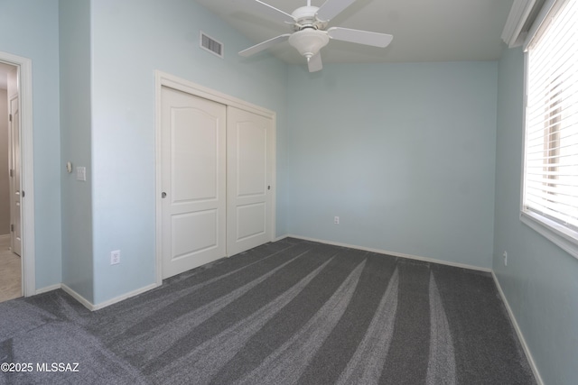 unfurnished bedroom featuring ceiling fan, a closet, and dark carpet