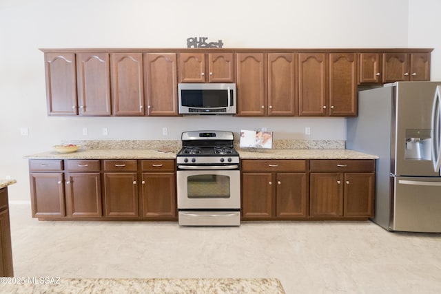 kitchen featuring stainless steel appliances and light stone counters