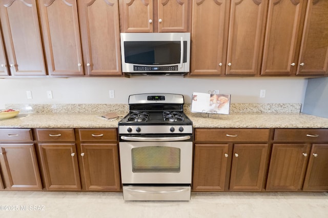 kitchen with light stone countertops and range with gas cooktop