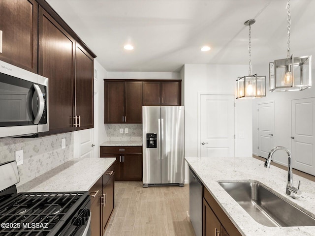 kitchen with light stone counters, stainless steel appliances, dark brown cabinets, and a sink