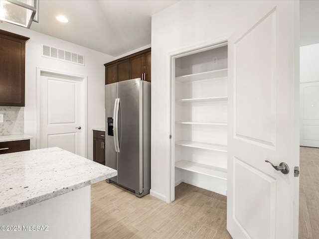 kitchen with visible vents, dark brown cabinets, stainless steel fridge with ice dispenser, and light wood-style flooring