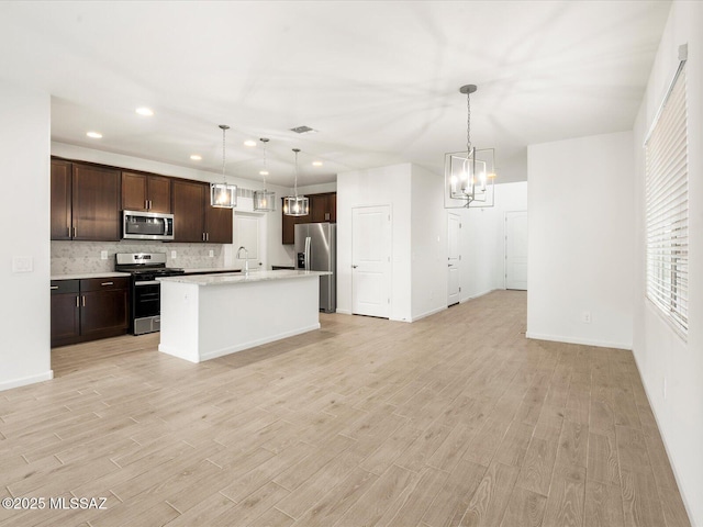 kitchen featuring dark brown cabinetry, light wood-type flooring, appliances with stainless steel finishes, and an inviting chandelier