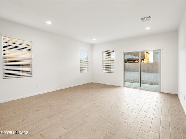 spare room with recessed lighting, visible vents, light wood-style flooring, and baseboards