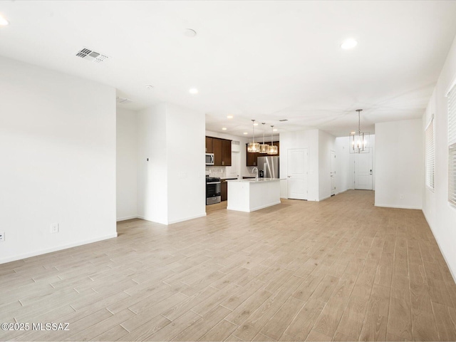 unfurnished living room featuring light wood-type flooring, visible vents, a notable chandelier, and recessed lighting