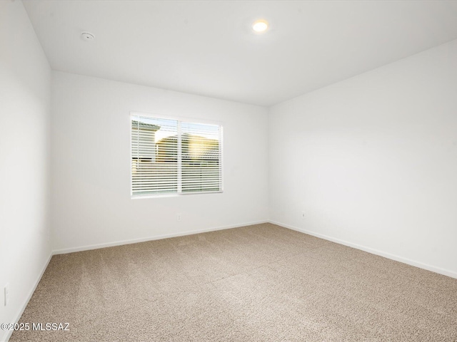 carpeted spare room featuring baseboards