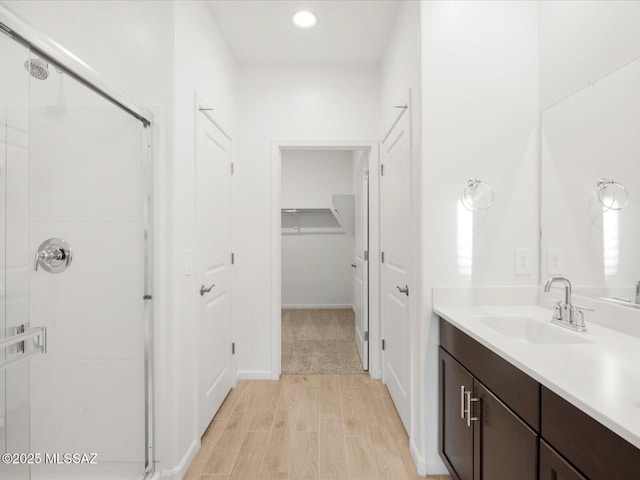 bathroom featuring recessed lighting, wood finished floors, a shower stall, and vanity
