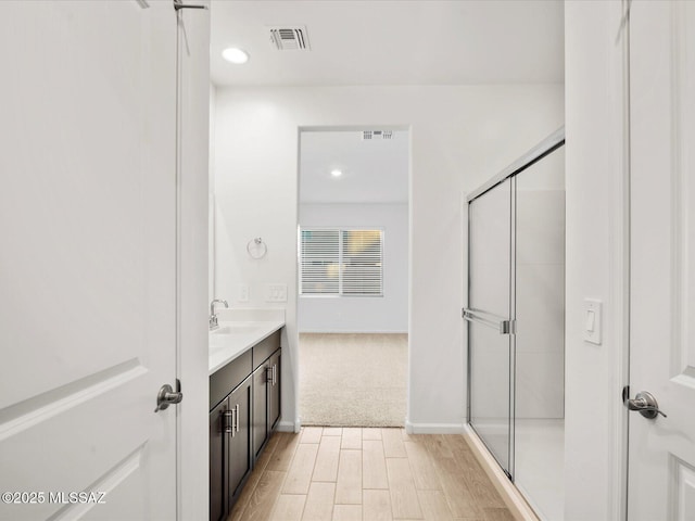 bathroom featuring visible vents, wood finished floors, a shower stall, and vanity