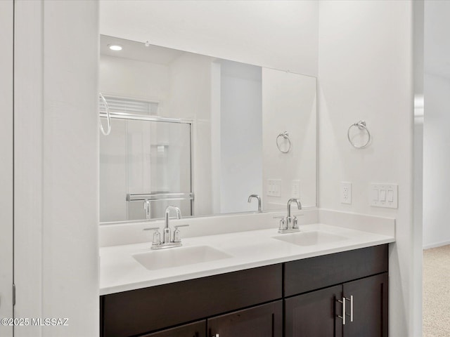 full bath featuring double vanity, a sink, and a shower stall