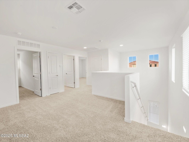 below grade area with baseboards, visible vents, and light colored carpet