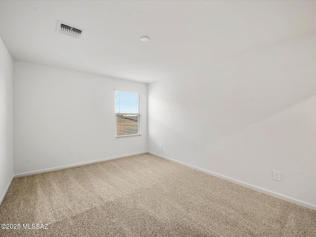 spare room with visible vents, carpet, and baseboards