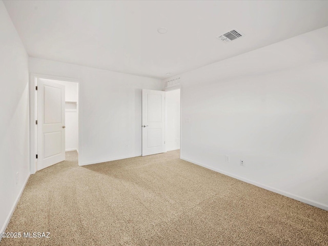 empty room with carpet, visible vents, and baseboards