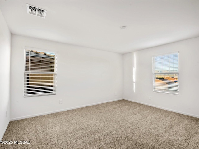 empty room with baseboards, visible vents, and carpet floors