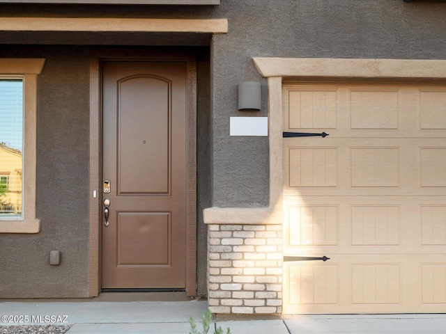 doorway to property featuring stucco siding and stone siding