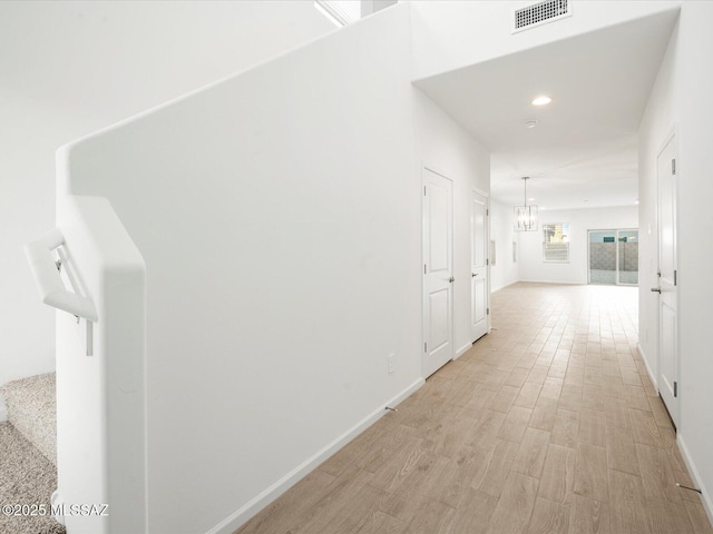 hallway featuring an inviting chandelier, visible vents, recessed lighting, and baseboards