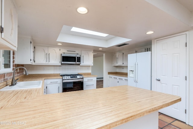 kitchen with stainless steel appliances, kitchen peninsula, sink, and white cabinets