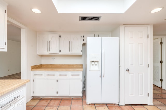 kitchen featuring light tile patterned flooring, white refrigerator with ice dispenser, and white cabinets