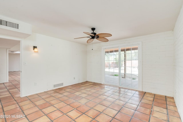 spare room with brick wall, light tile patterned floors, and ceiling fan