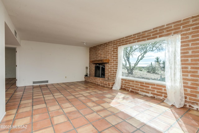 unfurnished living room with brick wall, a brick fireplace, and light tile patterned floors