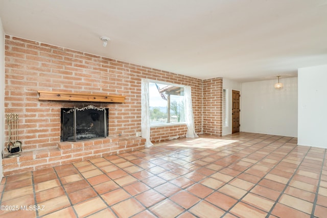 unfurnished living room with tile patterned flooring, brick wall, and a brick fireplace