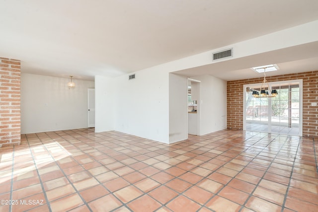 spare room with light tile patterned flooring, brick wall, and an inviting chandelier